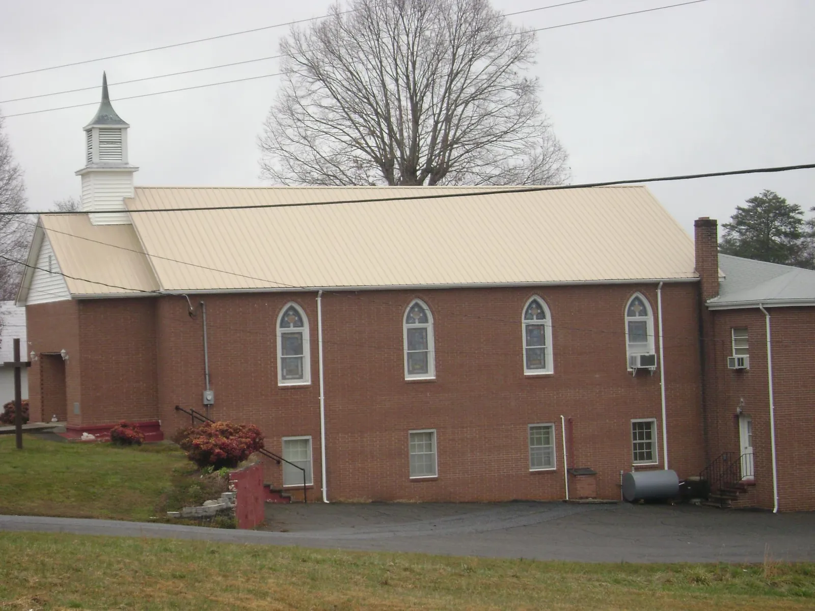 New tan metal roof on a brick church with a white steeple in Richland