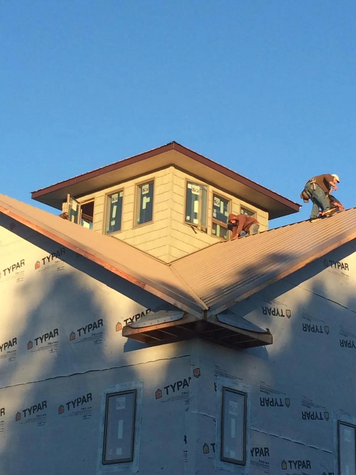 Roofers working around a rooftop cupola on a new metal roof at sunset — Roof Waterproofing in Richland by Roofing Brothers